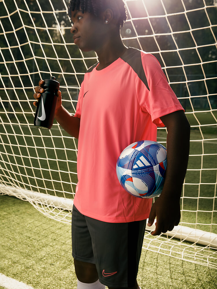 Ragazzo in campo da calcio con pallone in mano